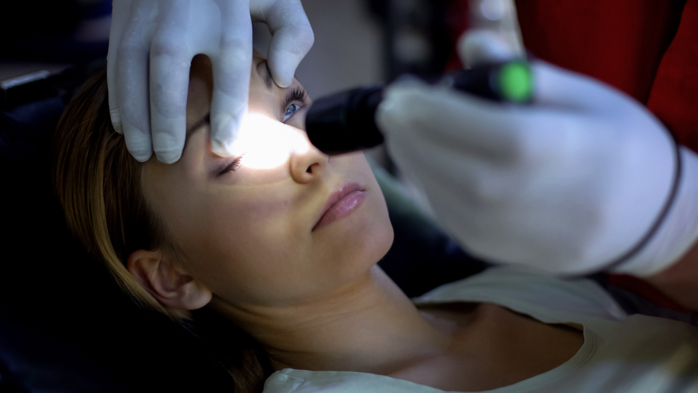 Doctor,Shining,Light,Into,Patient,Eye,,Testing,Pupil,Reflexes,,First