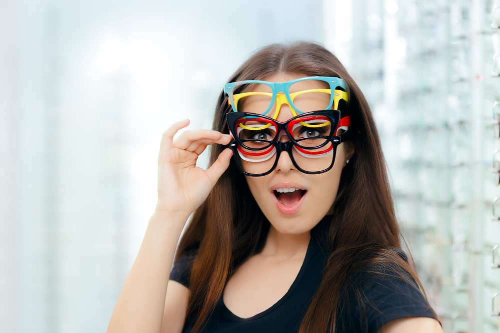 Funny,Woman,Trying,Many,Eyeglasses,Frames,In,Optical,Store,Happy