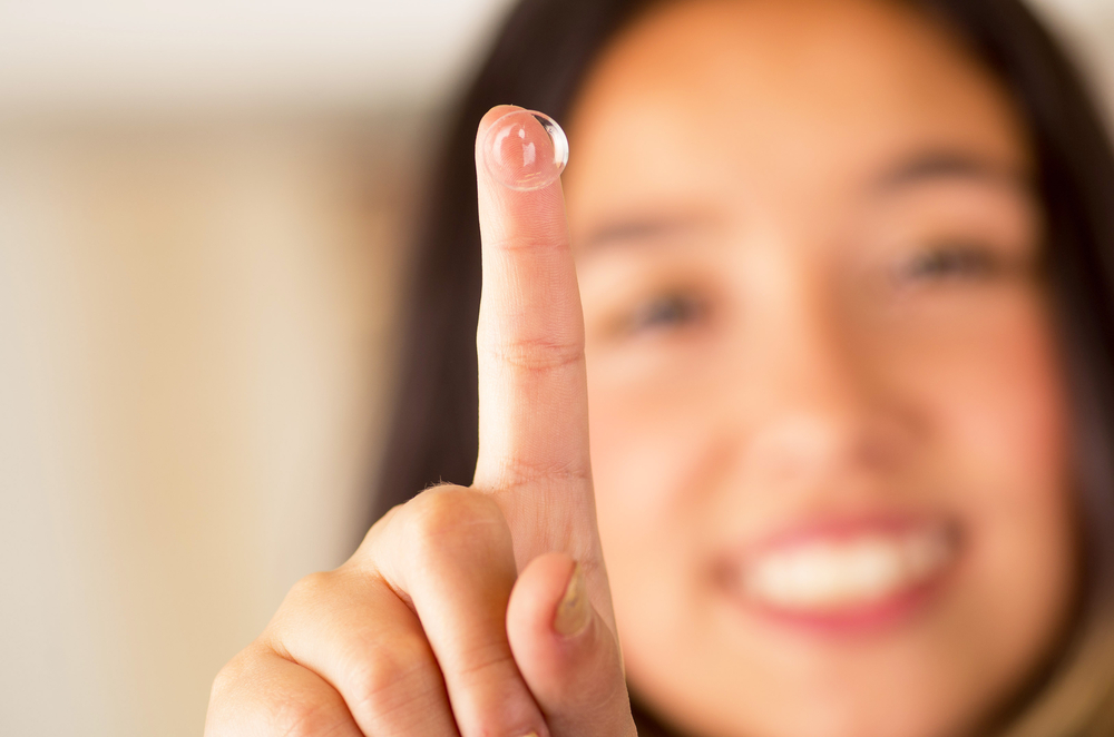 Contact,Lens,On,Finger,And,Beautiful,Woman,Smiling,Behind,On